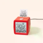 Dispositivo Stickerbox, una caja roja con pantalla y botón para hablar